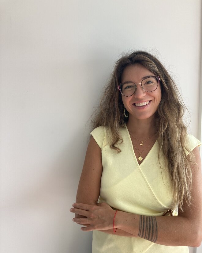 Paula Miravalles, pedagoga sistémica, sonriendo con los brazos cruzados